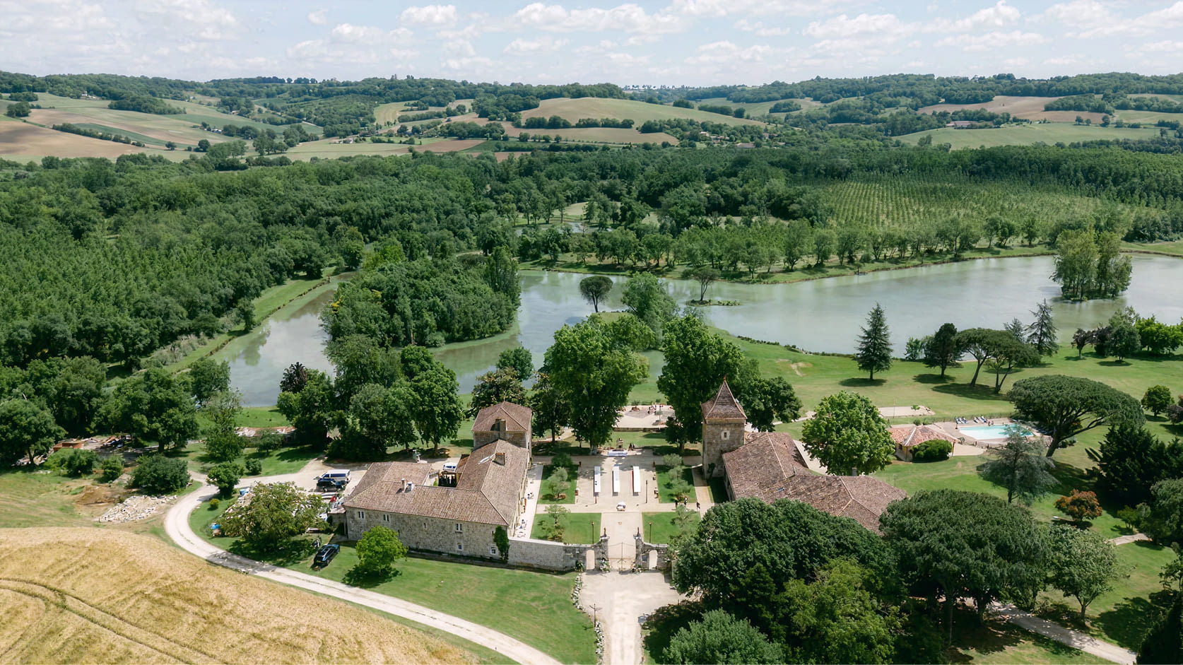drone view of buildings, park, lake and trees of domaine de boulouch